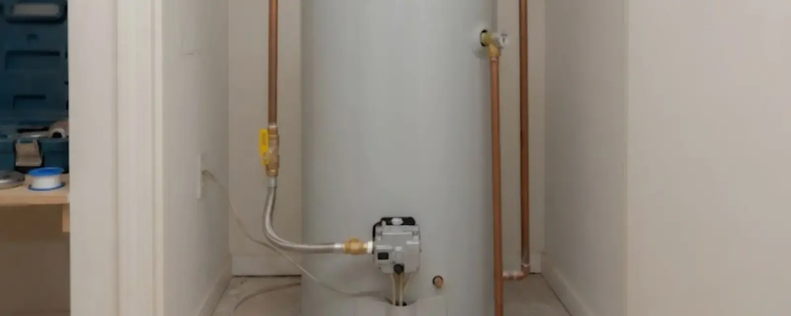 New tank water heater standing in a clean utility closet with copper connections