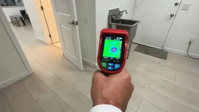 Hand holding a thermal imaging camera to check a wall for a hidden leak