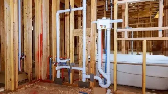 New rough-in plumbing with white drain pipes and supply lines in open wall framing